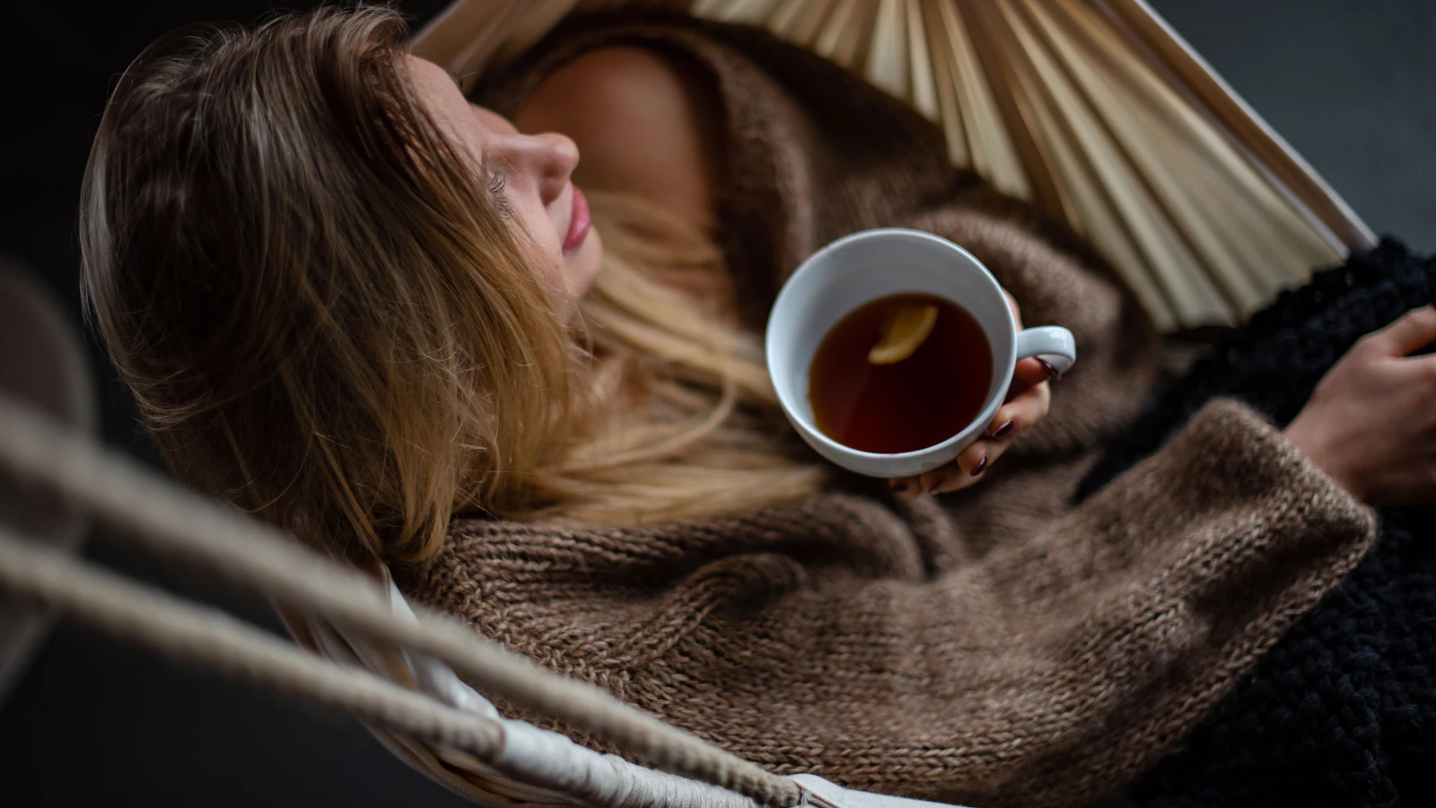 Vrouw rust uit in een hangmat met een kop koffie.