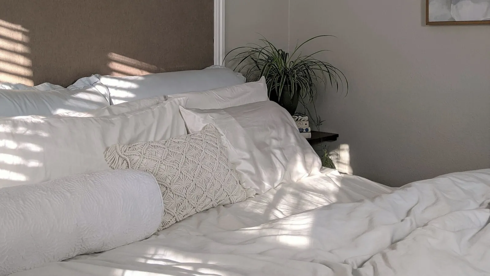Een opgemaakt bed met wit beddengoed in het zachte licht van de ochtend.