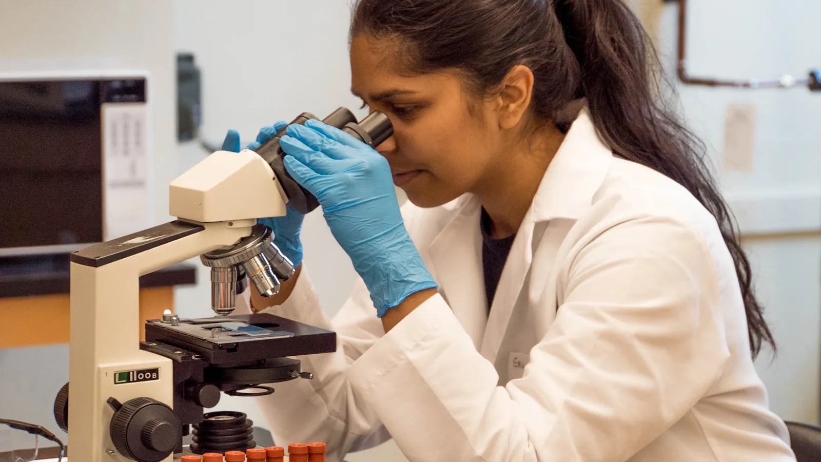 Onderzoeker kijkt door een microscoop in een laboratorium.