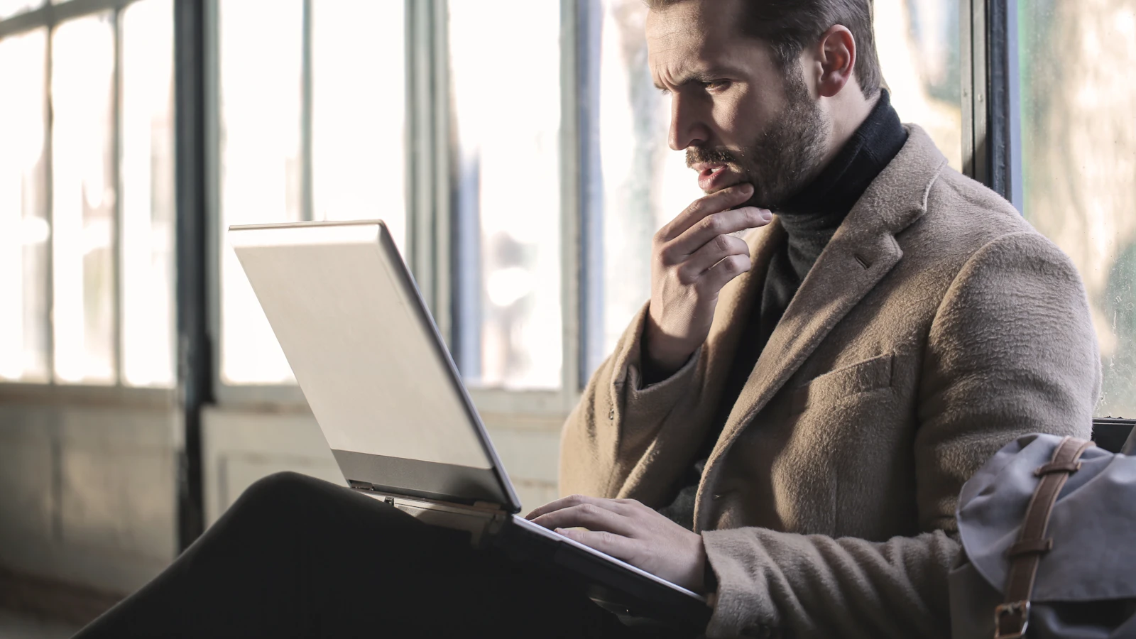 Iemand zit ongeconcentreerd achter een laptop bij daglicht, als beeld bij brain fog en concentratieproblemen.