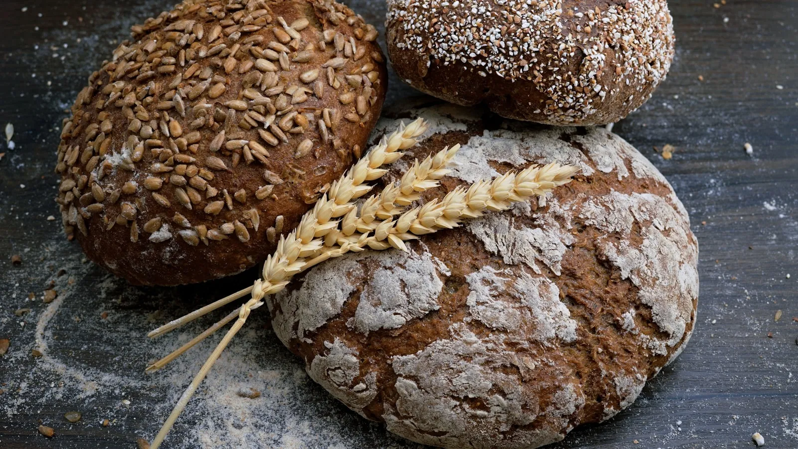 Persoon bekijkt een boterham terwijl brood en granen op tafel liggen, als beeld bij een coeliakie test.
