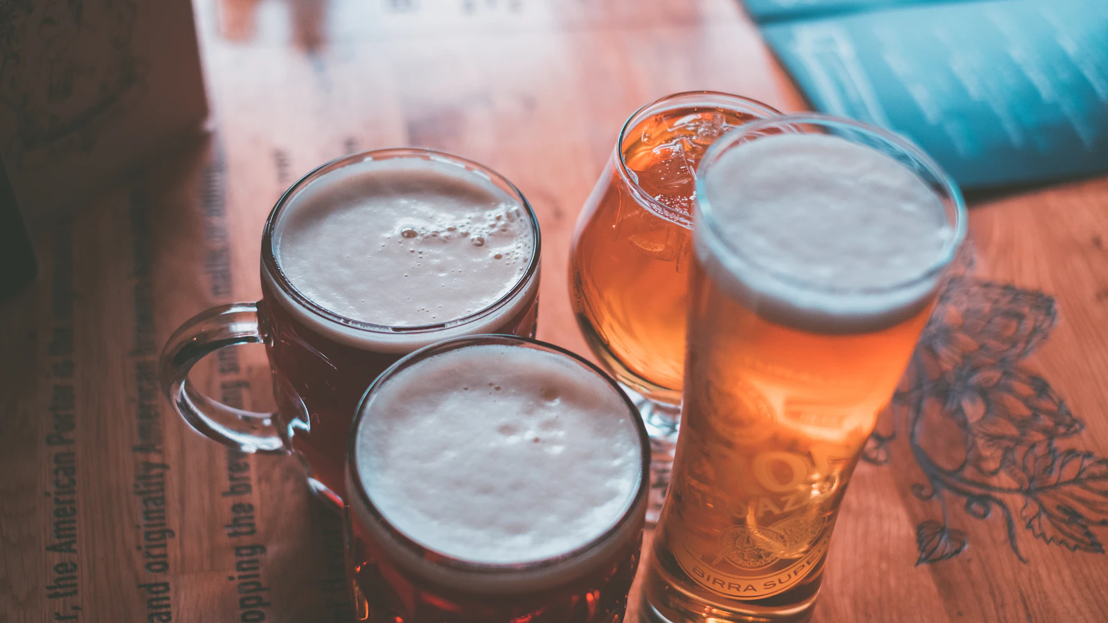 Glas bier en een blikje op een houten tafel.