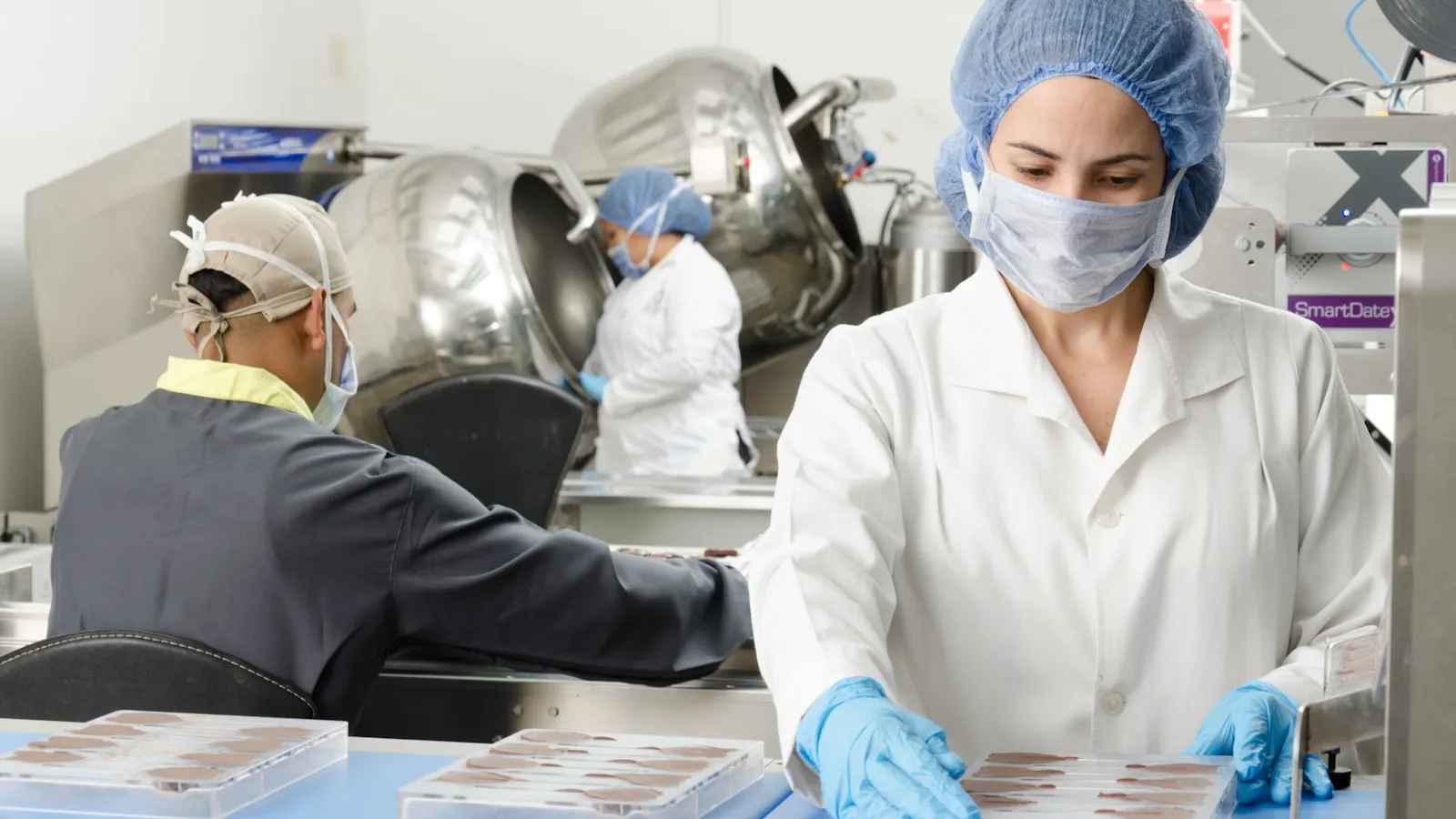 Laboratoriummedewerkers met mondkapjes en witte jassen aan het werk in een lab.