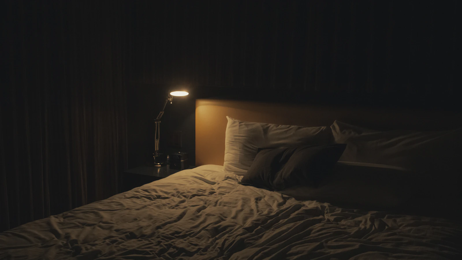 Slaapkamer in de nacht met een brandend bedlampje naast het bed.