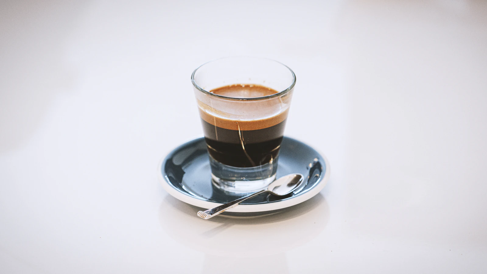 Cup of espresso on a saucer with a small spoon