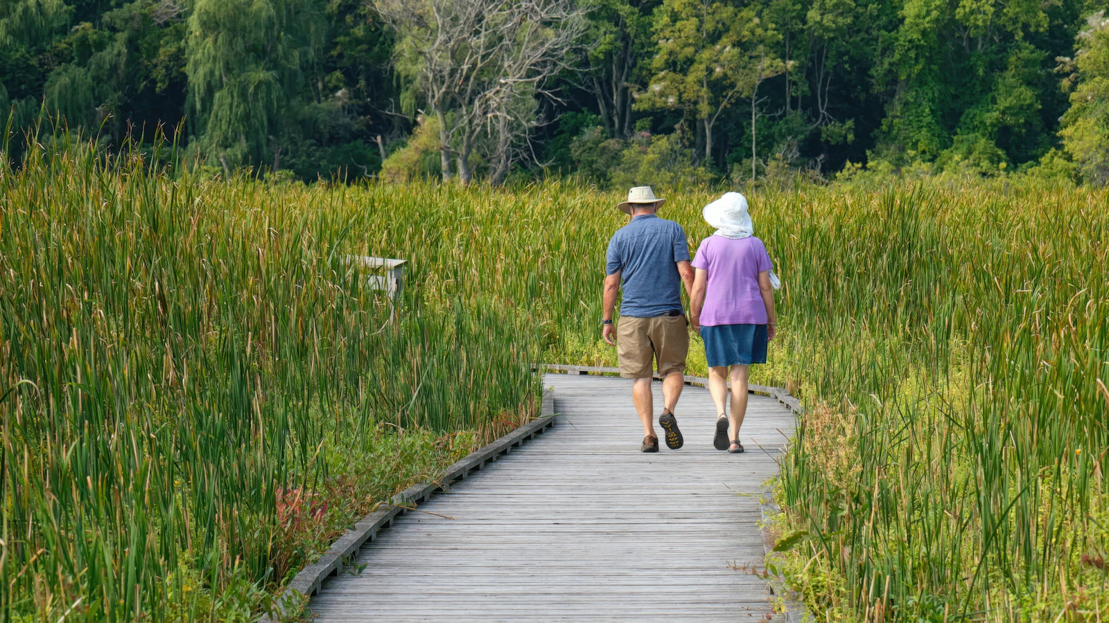 Een oudere en jongere persoon wandelen samen buiten in de natuur.