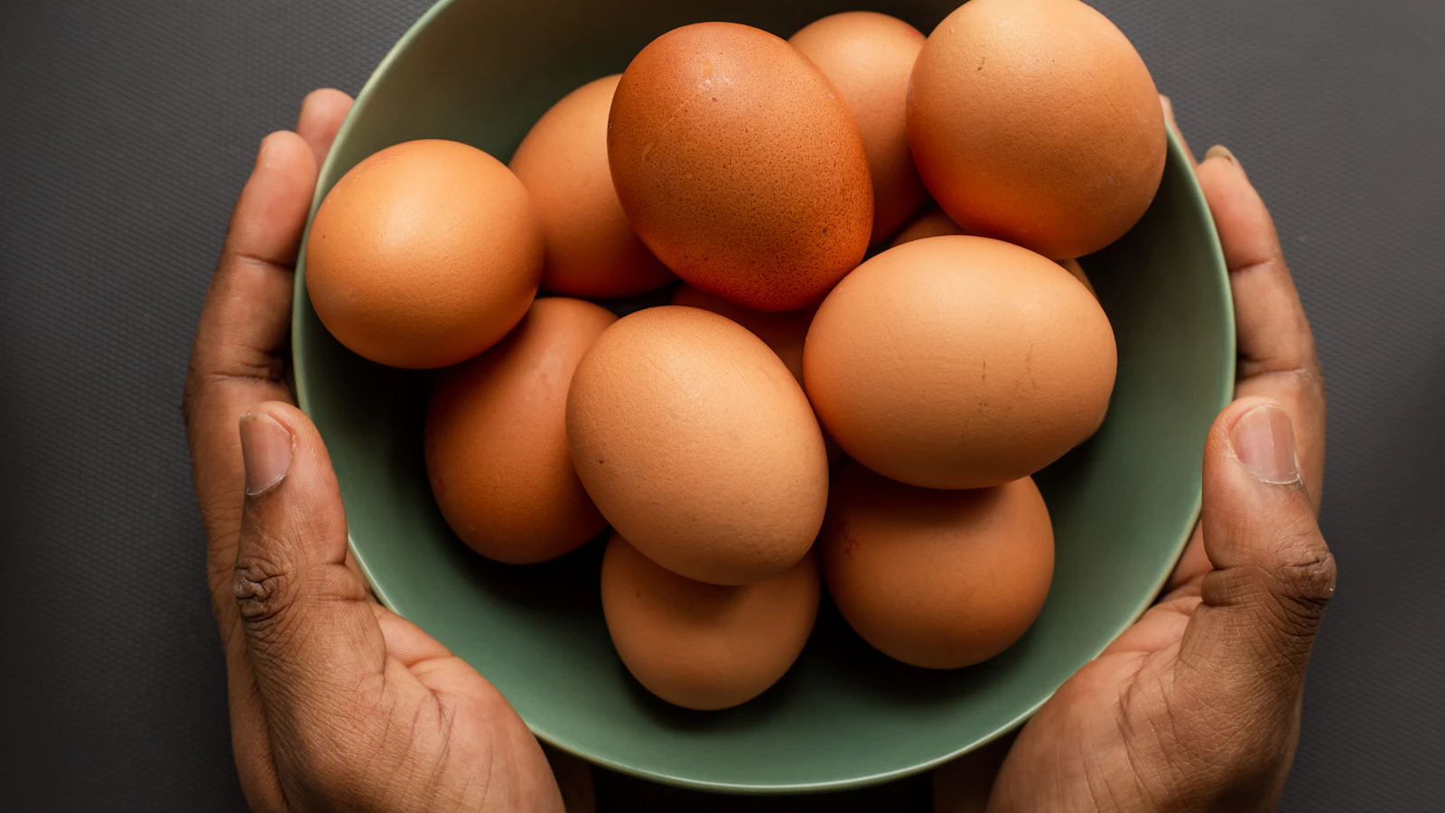 A brown egg in a green bowl as protein-rich food.