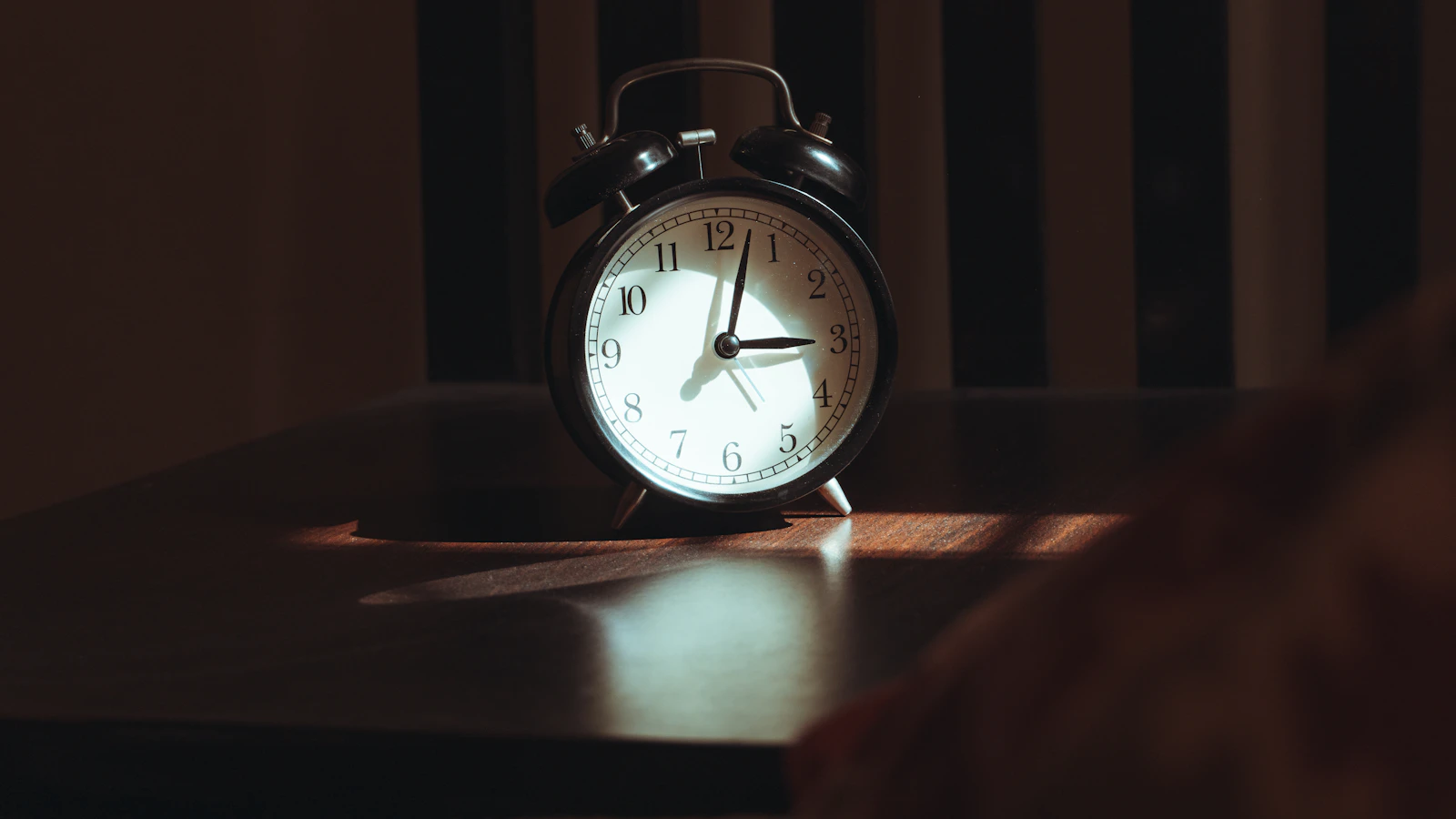 Someone lies awake in bed in morning light, as an image for being tired despite enough sleep.