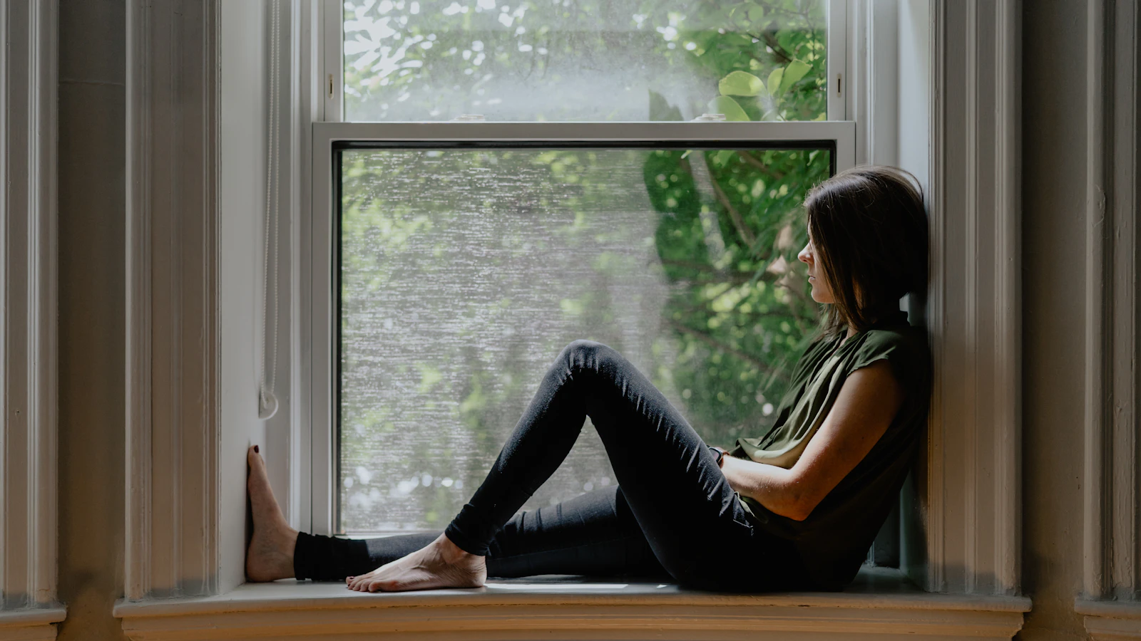 Woman sitting calmly by a window, illustrating menopause and hormonal change.