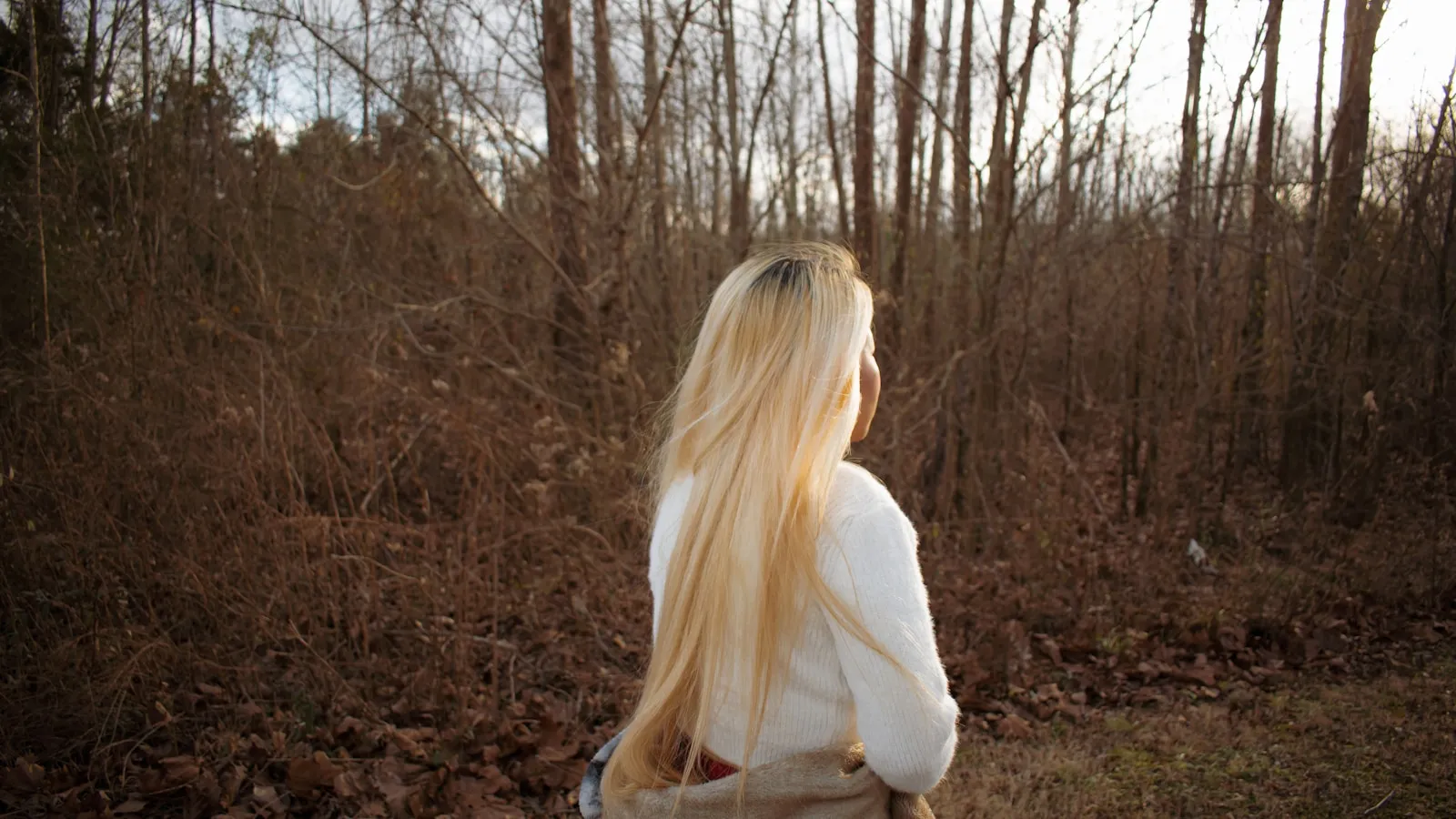 Vrouw in een wit shirt wandelt in het daglicht over een open veld.