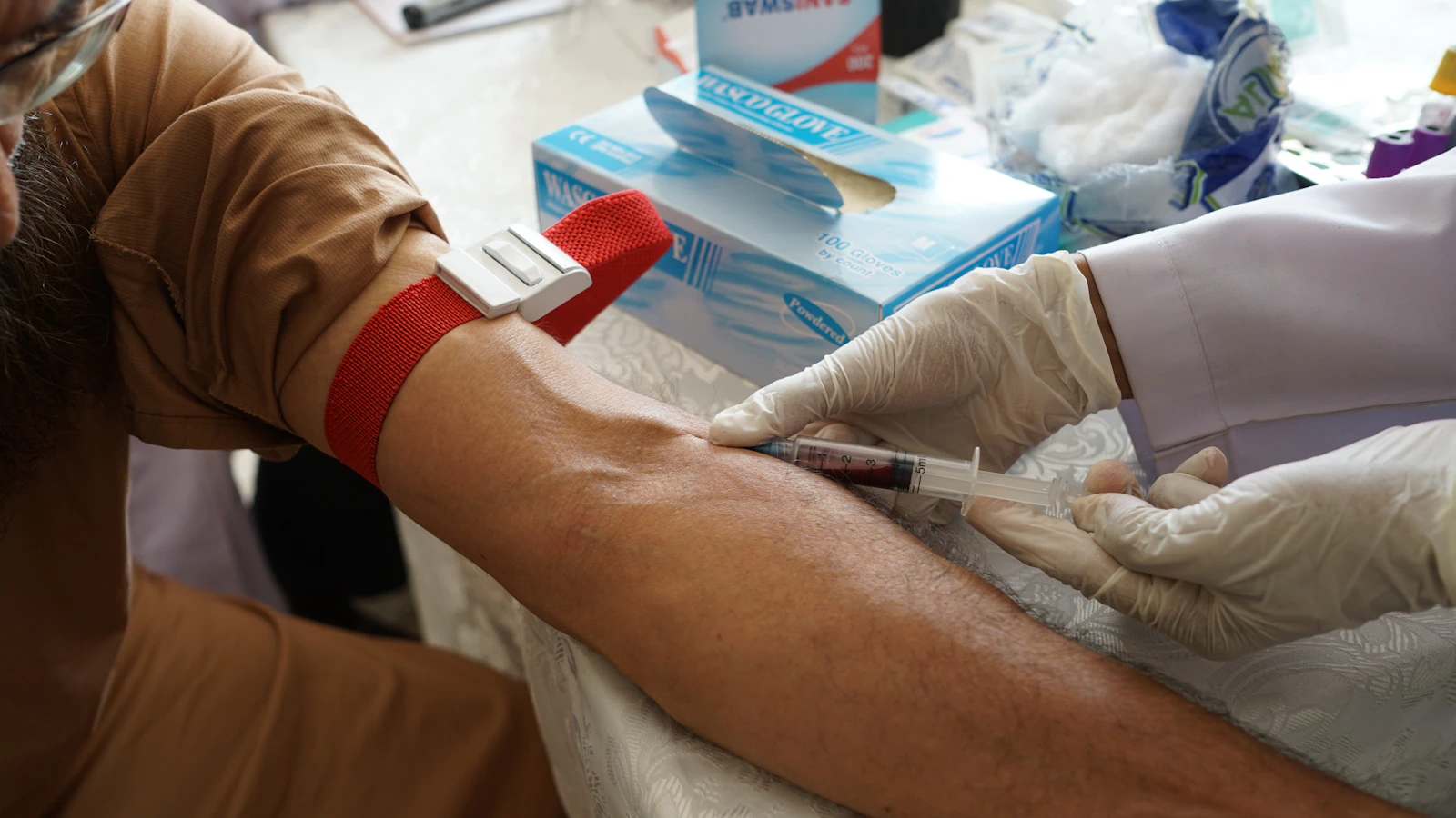Zorgverlener neemt bloed af uit de arm van een patiënt in een kliniek.