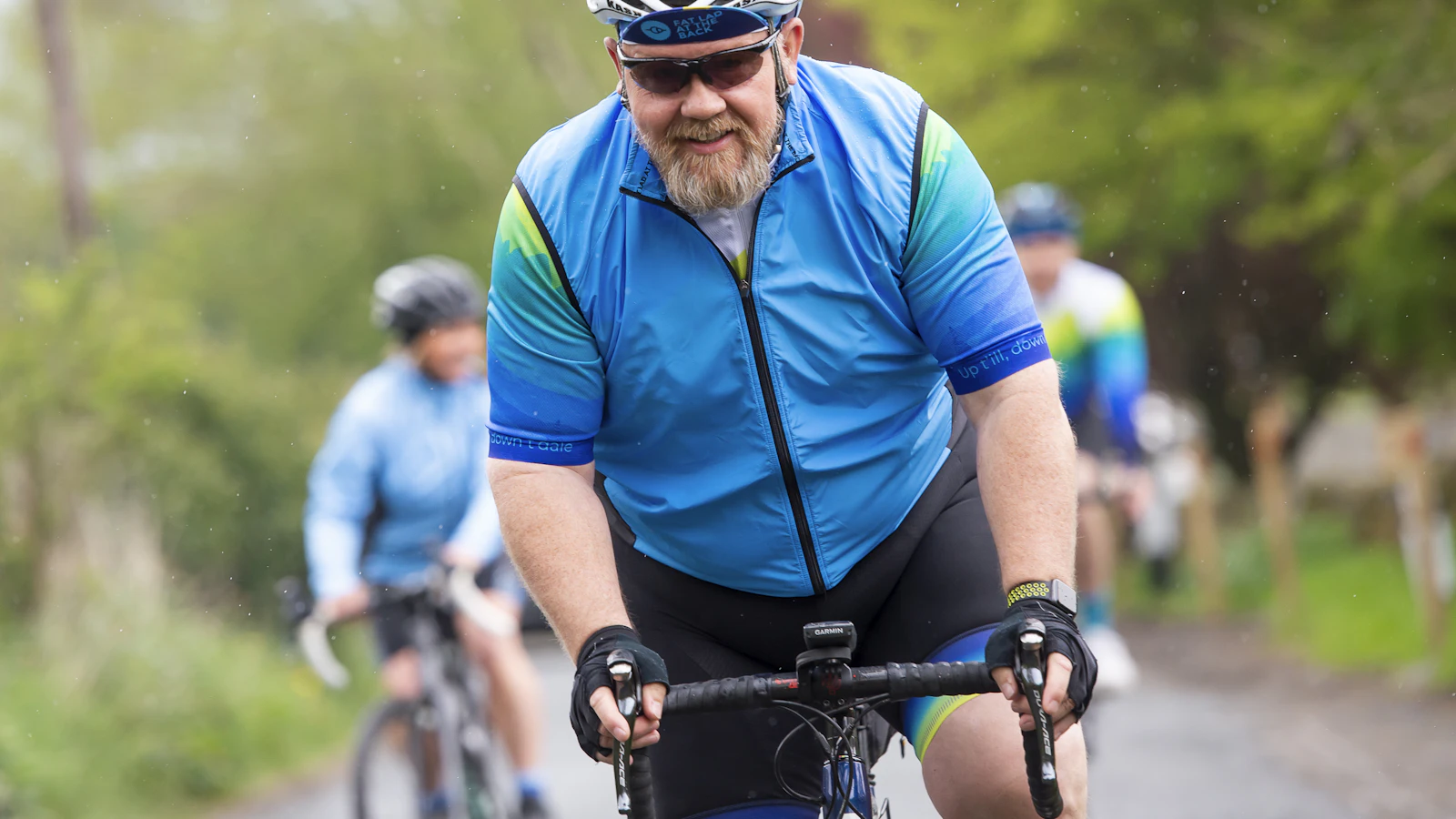 Een man fietst op een weg langs een bos in de ochtend.
