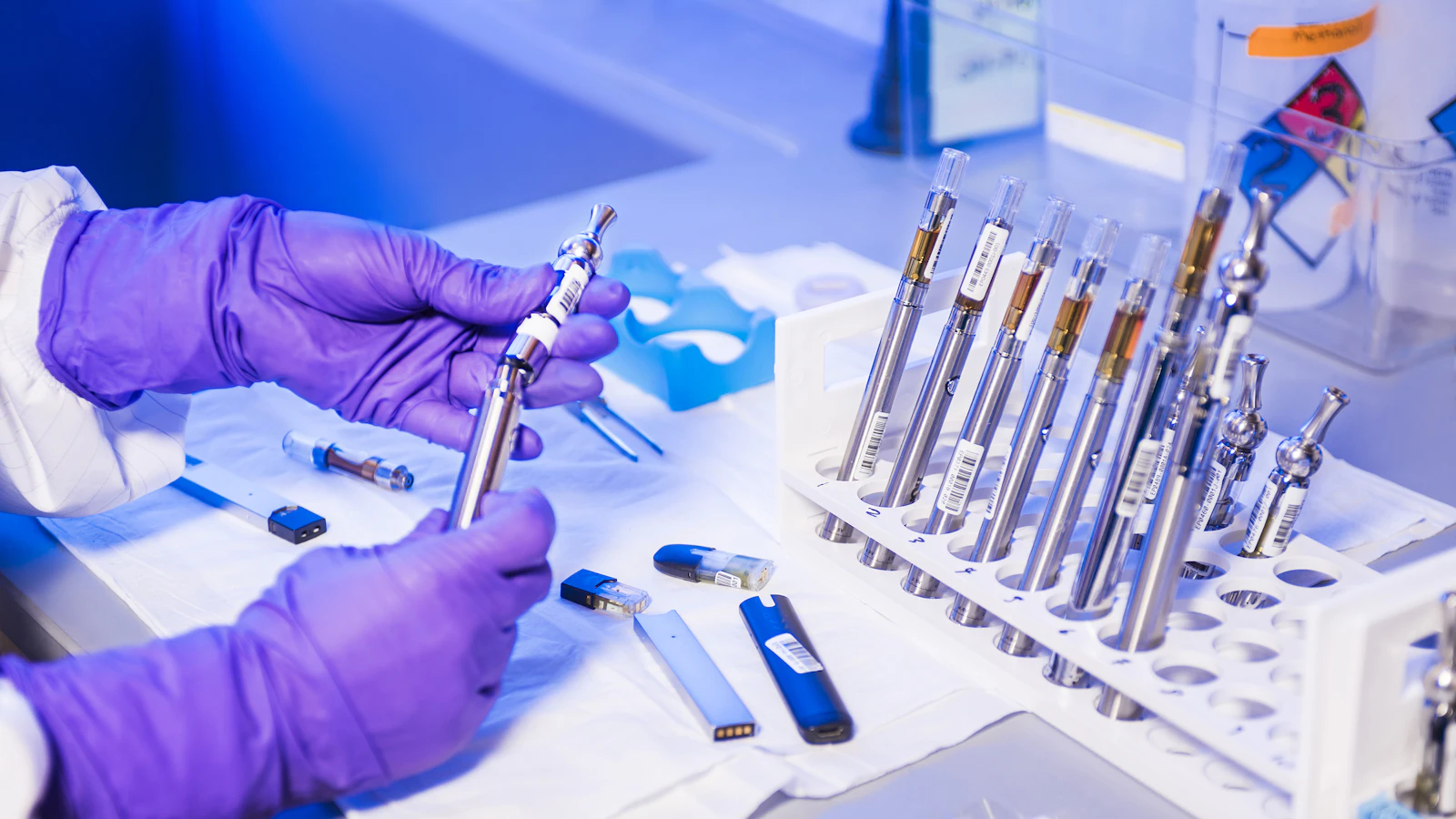 A gloved hand holds a tube of blood in a laboratory.