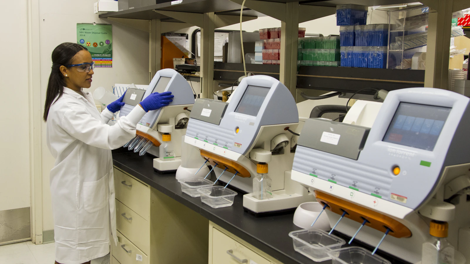 Laborant in beschermende kleding bij een laboratoriumapparaat.